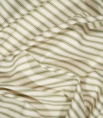 JF Ticking Sap Green fabric draped in soft folds, highlighting the classic olive green ticking stripe pattern, woven texture and natural drape.