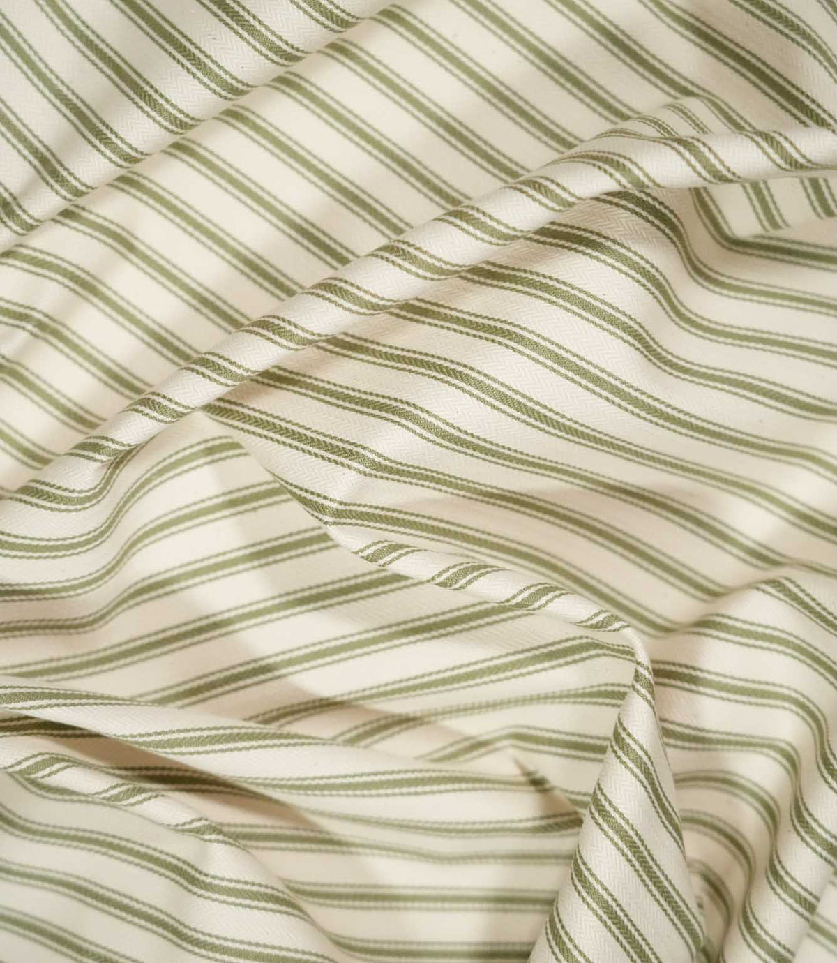 JF Ticking Sap Green fabric draped in soft folds, highlighting the classic olive green ticking stripe pattern, woven texture and natural drape.
