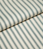 Close-up of folded JF Ticking Teal fabric showing dark teal ticking stripes against a cream ground with a subtle herringbone weave.