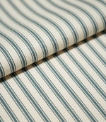 Detailed close-up of JF Ticking Teal striped fabric arranged in a soft fold, highlighting the repeating teal stripes and fine woven herringbone texture.