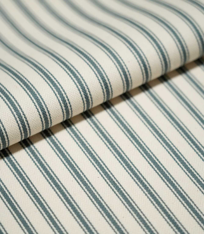 Detailed close-up of JF Ticking Teal striped fabric arranged in a soft fold, highlighting the repeating teal stripes and fine woven herringbone texture.