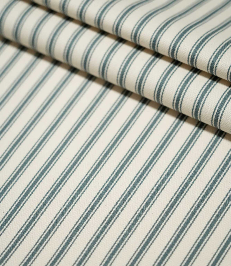 JF Ticking Teal fabric arranged in layered folds, showing the repeating dark teal ticking stripe pattern across the cream woven background.