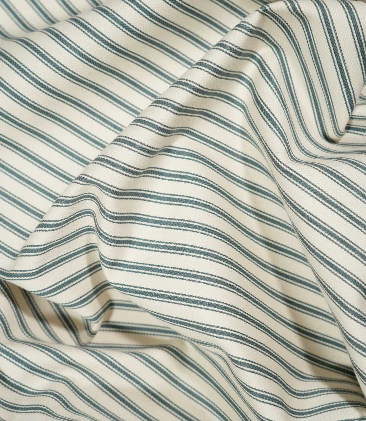 JF Ticking Teal striped fabric draped in loose folds, showing the classic teal ticking design, cream background and natural movement of the fabric.