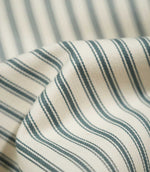 Close-up of draped JF Ticking Teal fabric highlighting the dark teal double stripes, cream ground and subtle herringbone woven texture.