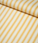 Close-up of JF Ticking Turmeric fabric folded over itself, highlighting the golden yellow ticking stripes, warm cream background and subtle herringbone woven texture.