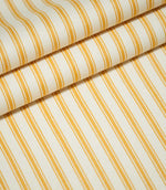 JF Ticking Turmeric fabric arranged in overlapping folds, showing the repeating golden yellow ticking stripes, fine parallel lines and textured cream herringbone weave.