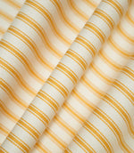 JF Ticking Turmeric striped fabric draped into soft, flowing folds, displaying the classic turmeric yellow and cream ticking stripe design and subtle herringbone texture.