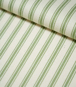 Close-up of JF Ticking Warm Green fabric folded over itself, highlighting the sage green ticking stripes, natural cream background and subtle herringbone woven texture.