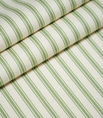 JF Ticking Warm Green fabric arranged in overlapping folds, showing the repeating sage green vertical stripes, fine contrasting lines and textured cream herringbone weave.