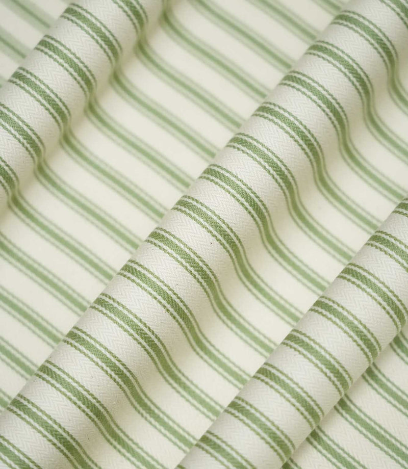 JF Ticking Warm Green striped fabric draped into soft, flowing folds, displaying the classic sage green and cream ticking stripe pattern and subtle herringbone texture.