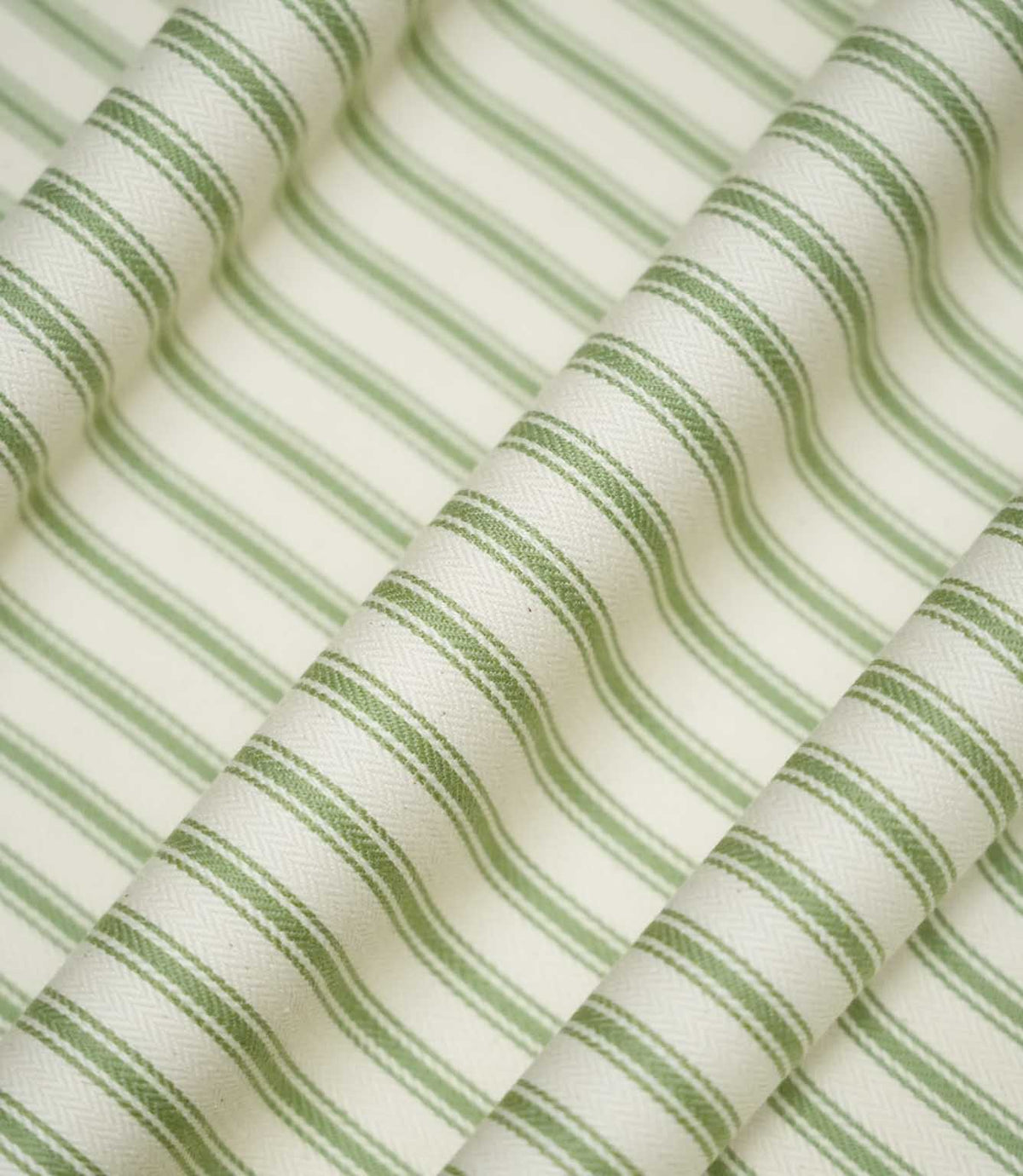 JF Ticking Warm Green striped fabric draped into soft, flowing folds, displaying the classic sage green and cream ticking stripe pattern and subtle herringbone texture.