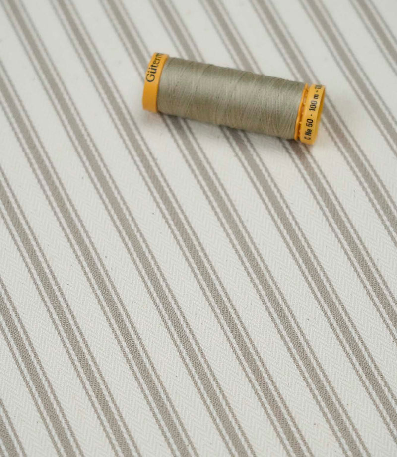 Beige ticking stripe fabric with matching beige thread, ideal for upholstery, curtains, blinds and sewing projects.