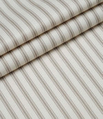 Layered folds of beige ticking stripe fabric displaying the fine herringbone weave and timeless striped pattern.