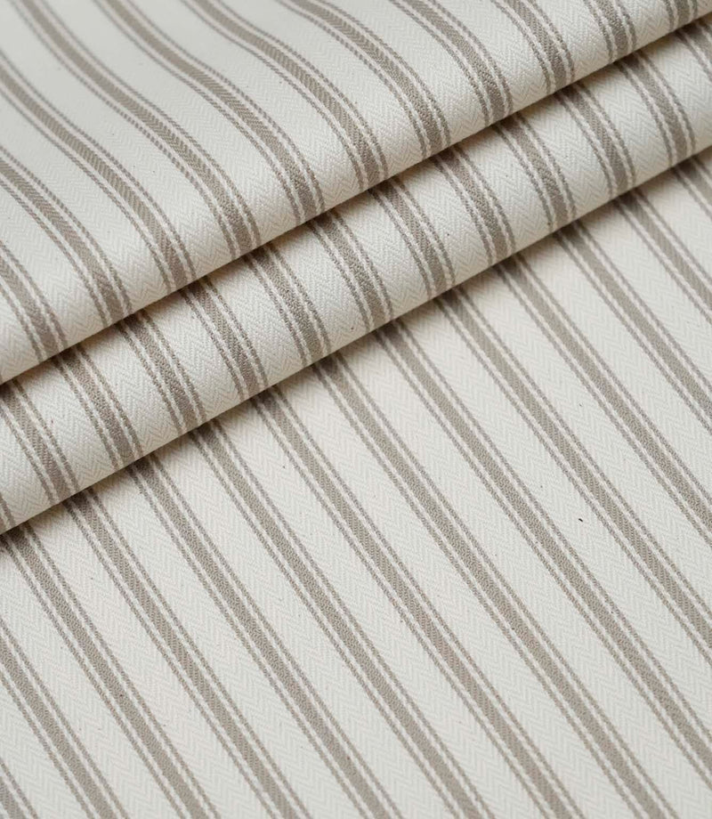 Layered folds of beige ticking stripe fabric displaying the fine herringbone weave and timeless striped pattern.