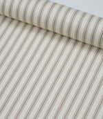 Rolled beige ticking stripe fabric highlighting the elegant neutral stripes and soft woven finish.