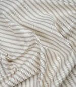 Beige ticking stripe fabric draped to show its soft handle, classic stripe design and subtle herringbone texture.