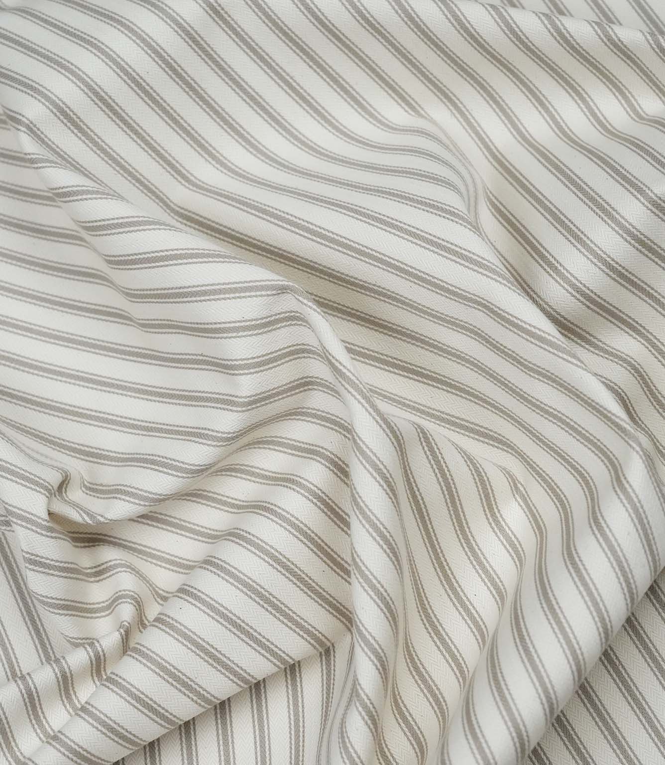 Beige ticking stripe fabric draped to show its soft handle, classic stripe design and subtle herringbone texture.