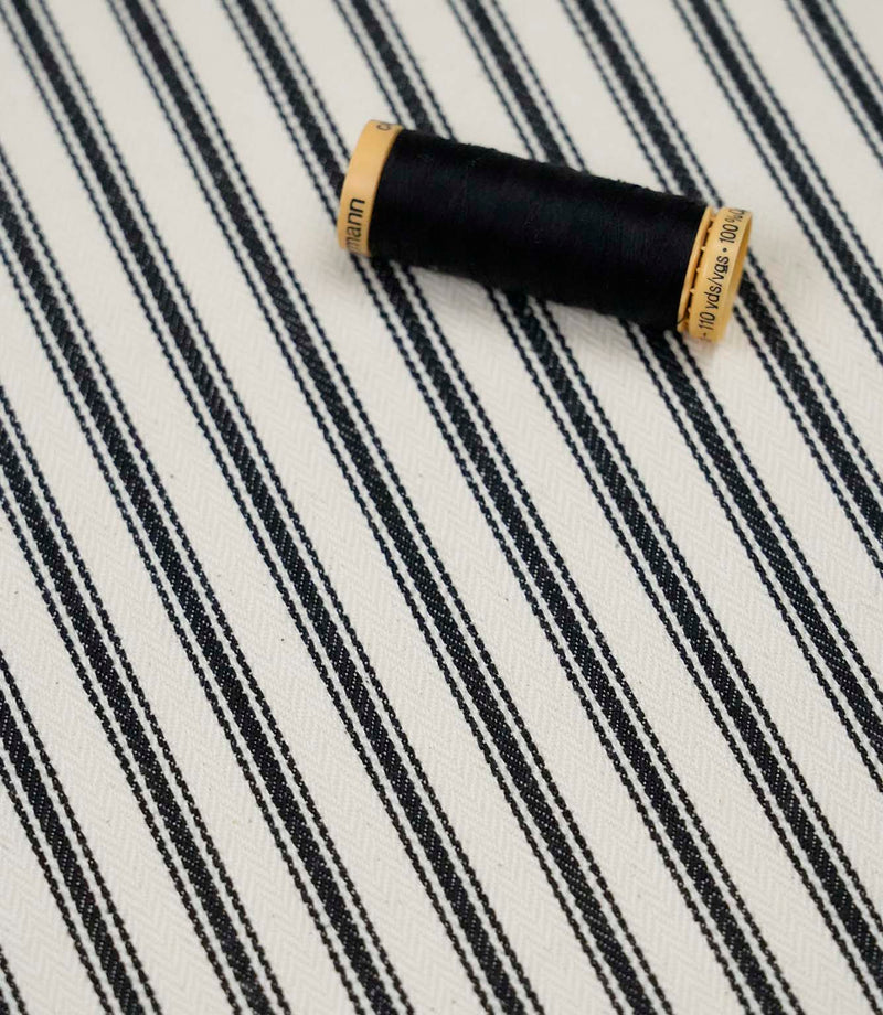 Black ticking stripe fabric with matching black thread, ideal for upholstery, curtains, blinds and sewing projects.