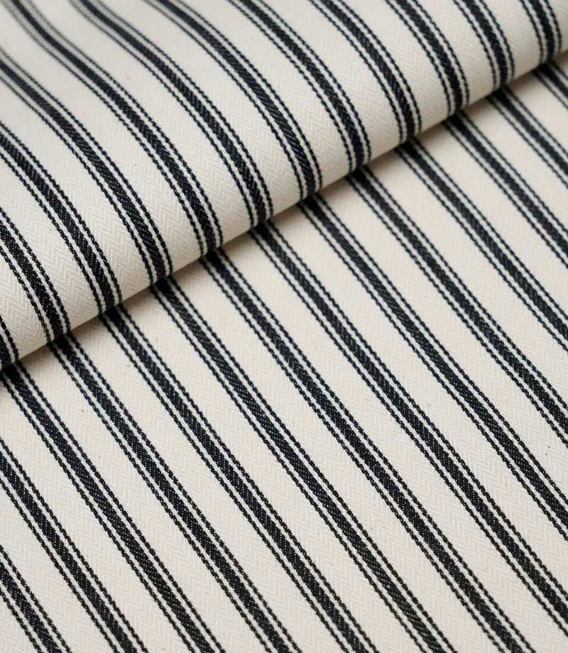 Folded black ticking stripe fabric showcasing the timeless striped pattern and premium woven finish.