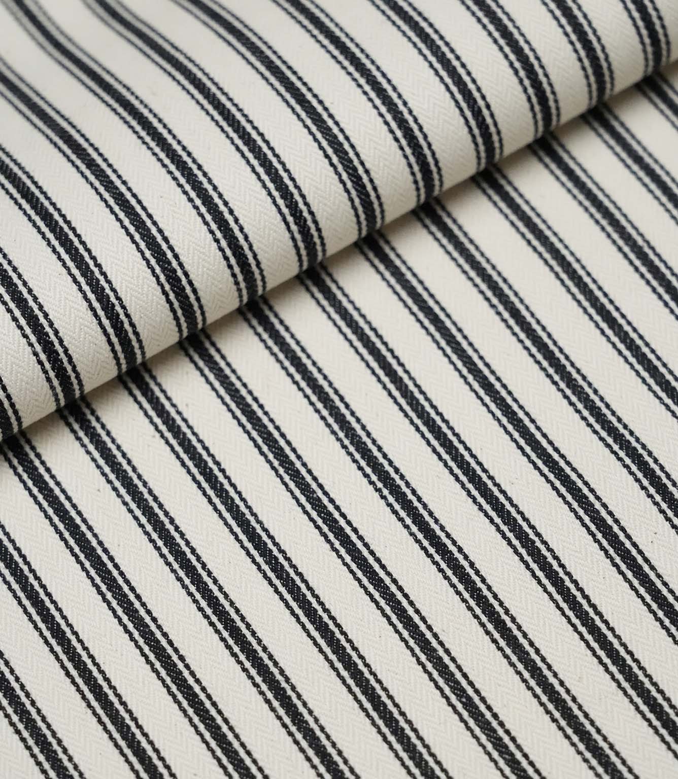 Folded black ticking stripe fabric showcasing the timeless striped pattern and premium woven finish.