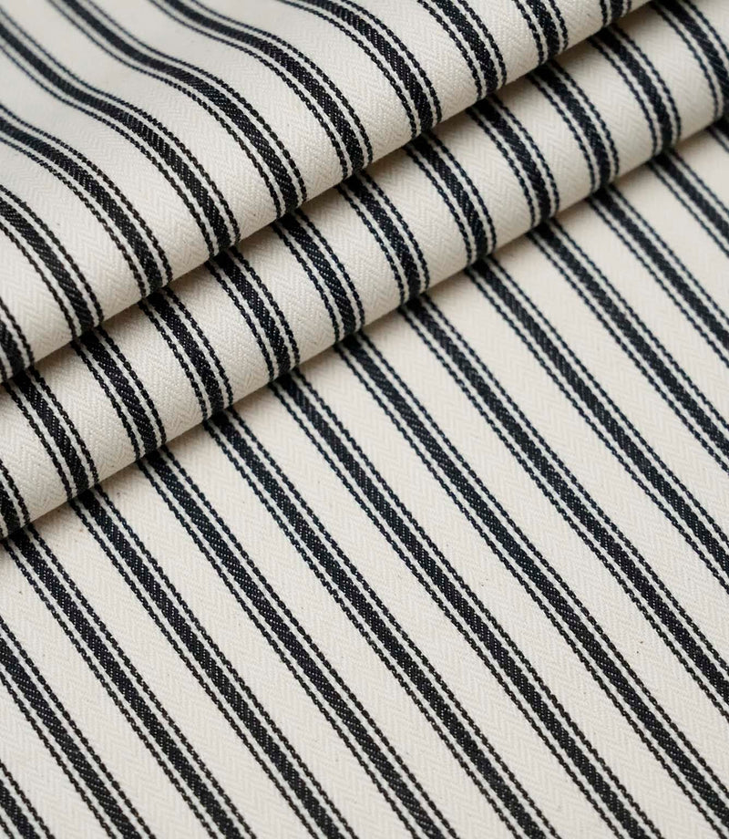 Layered folds of black ticking stripe fabric displaying the fine herringbone weave and classic striped design.