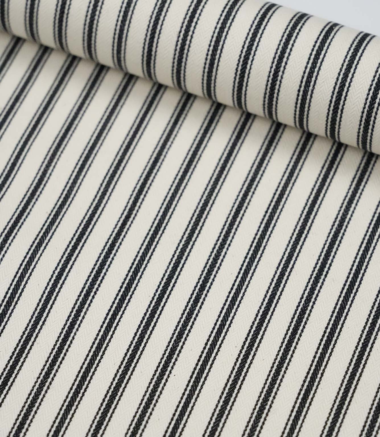 Rolled black ticking stripe fabric highlighting the bold monochrome stripes and subtle woven texture.