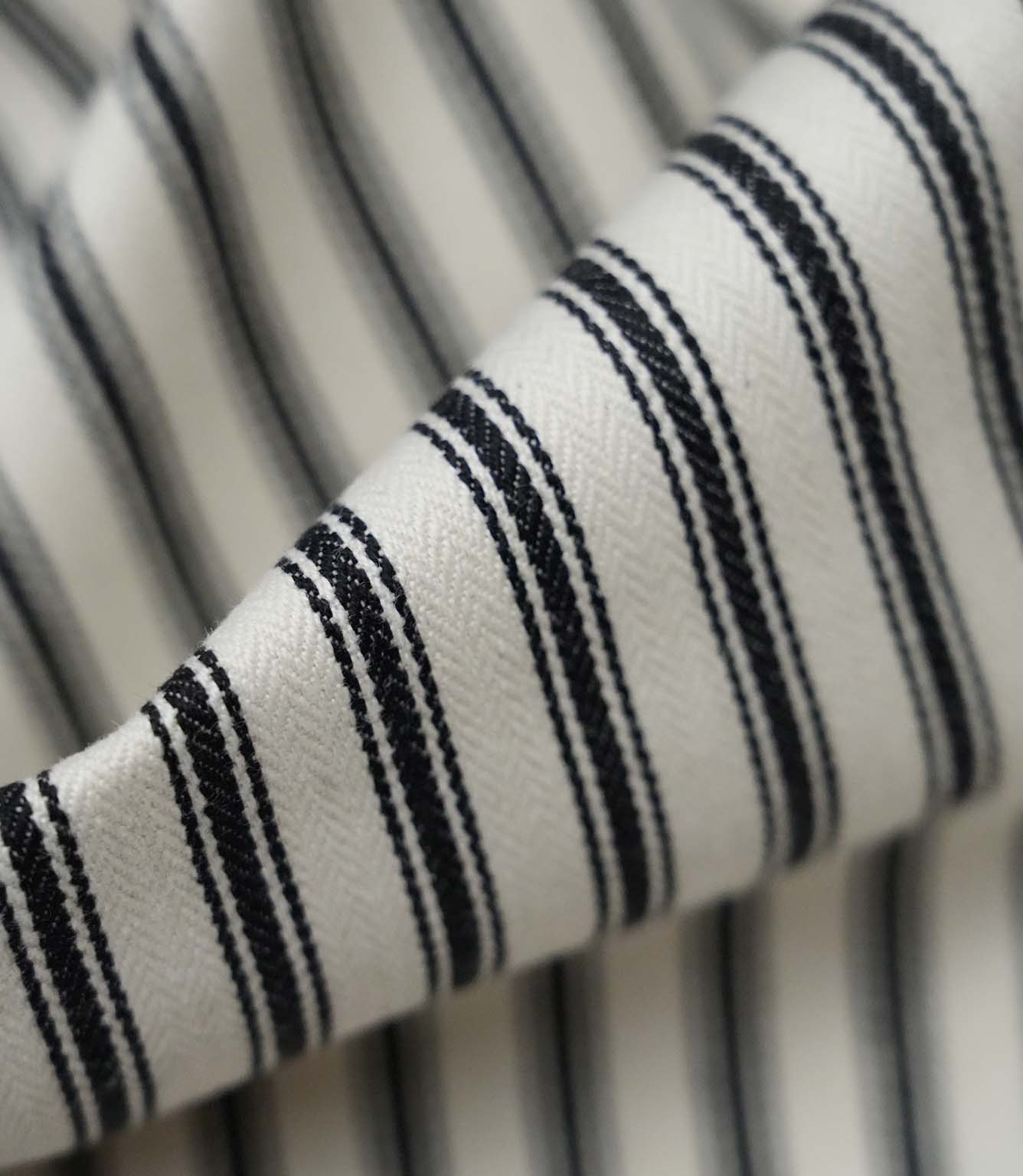 Close-up detail of black ticking stripe fabric showing the fine woven texture and bold black stripe pattern.