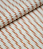 Folded burnt orange ticking stripe fabric showcasing the timeless striped pattern and premium woven finish.