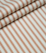 Layered folds of burnt orange ticking stripe fabric displaying the fine herringbone weave and classic striped design.
