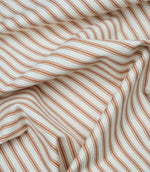 Burnt orange ticking stripe fabric draped to show its soft handle, classic stripe pattern and woven herringbone texture.
