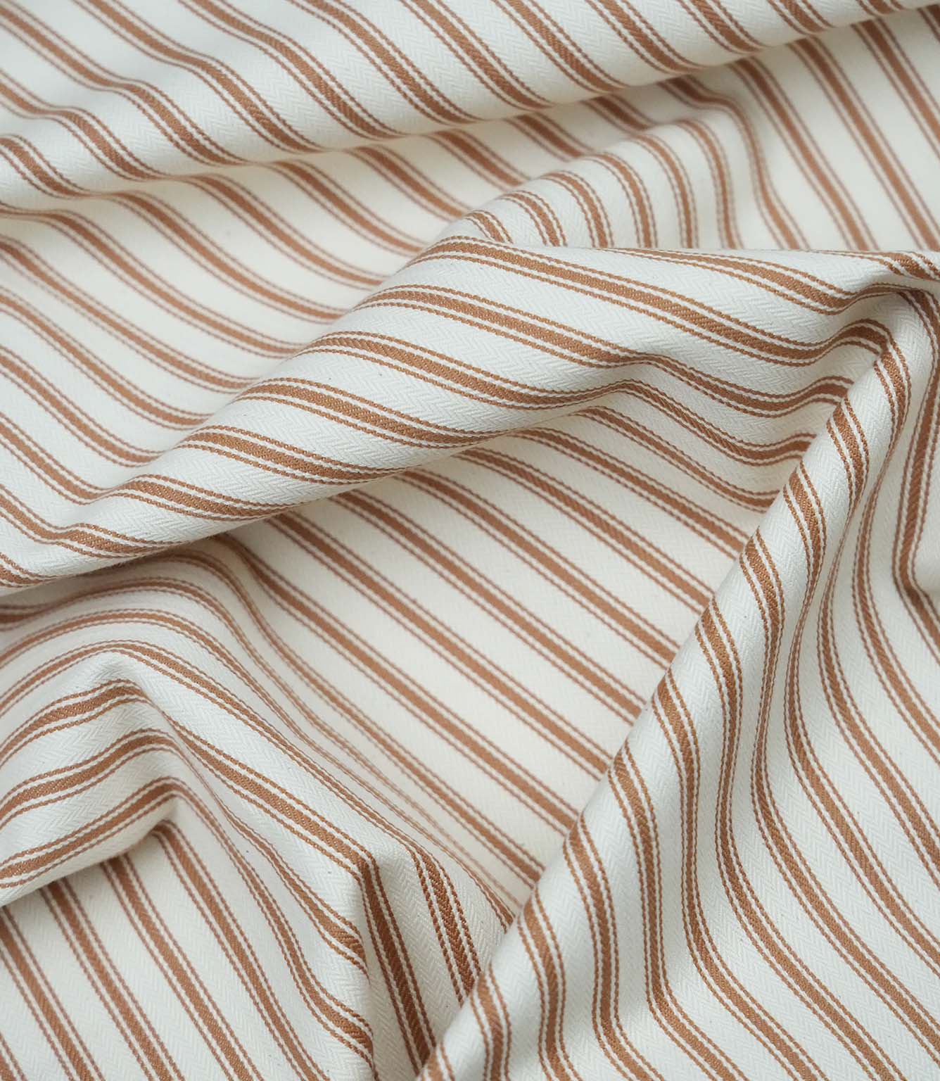 Burnt orange ticking stripe fabric draped to show its soft handle, classic stripe pattern and woven herringbone texture.