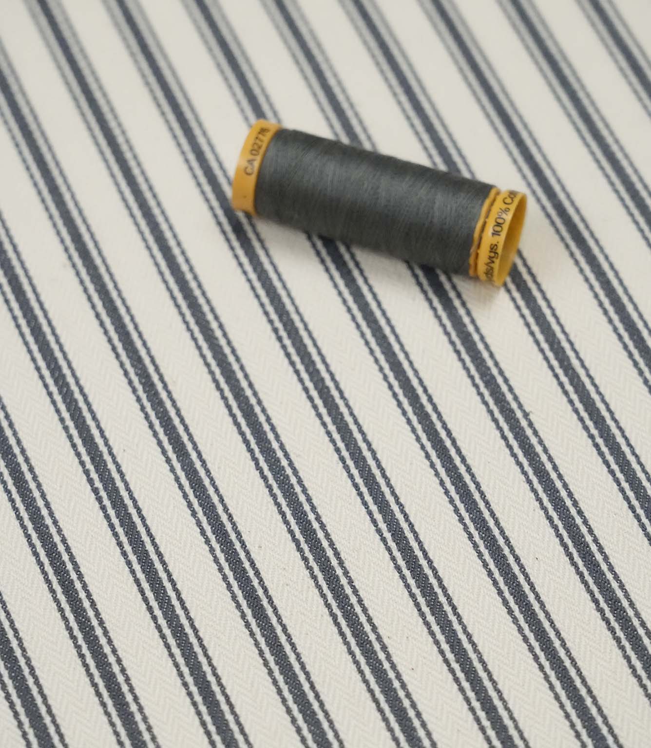 Grey ticking stripe fabric with matching grey thread, ideal for upholstery, curtains, blinds and sewing projects.