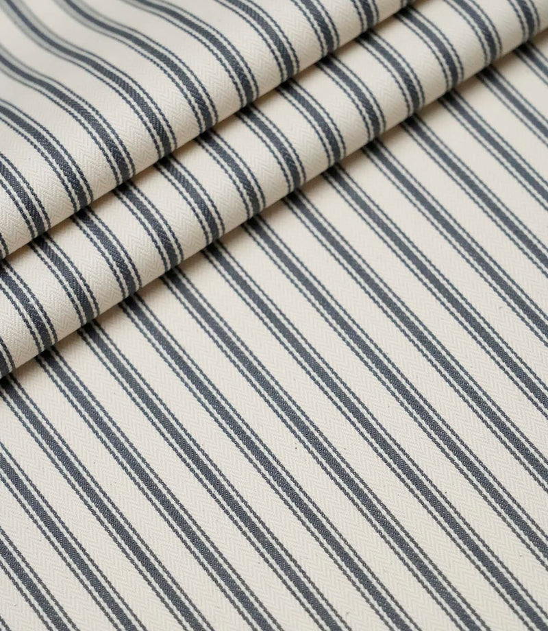 Layered folds of grey ticking stripe fabric displaying the fine herringbone weave and classic striped design.