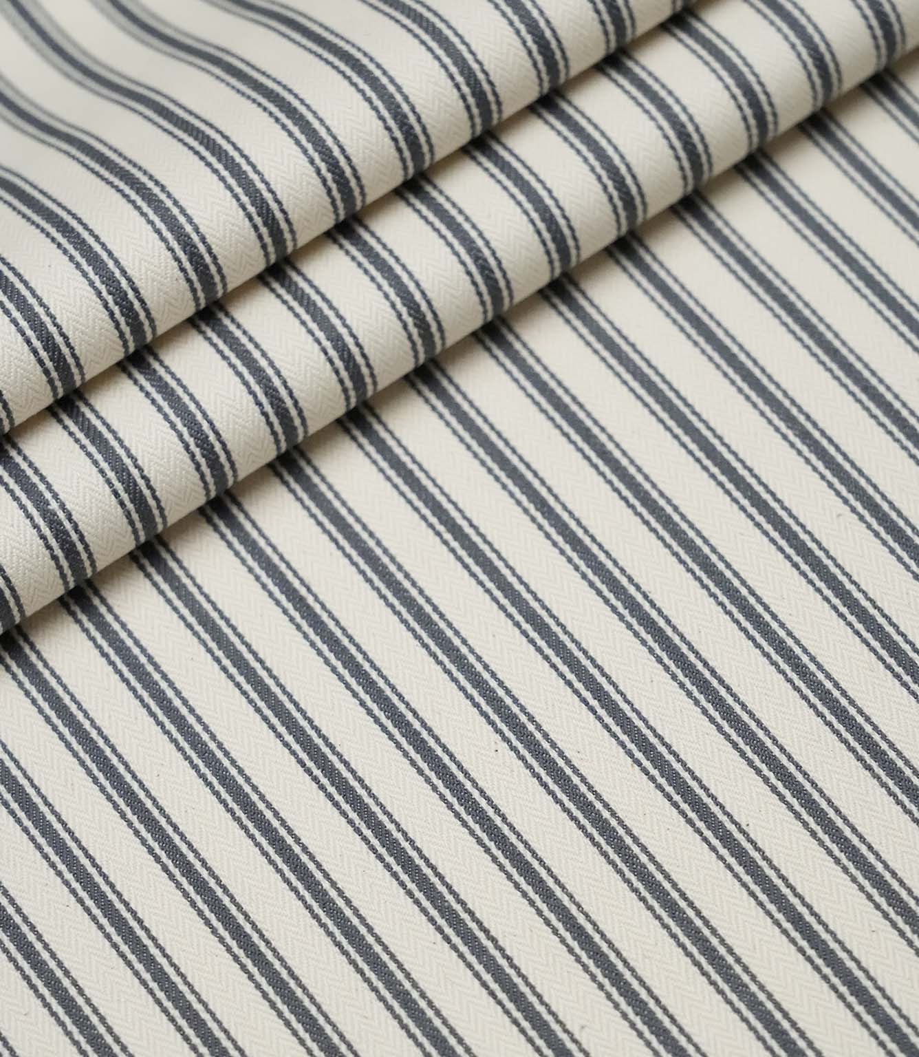 Layered folds of grey ticking stripe fabric displaying the fine herringbone weave and classic striped design.