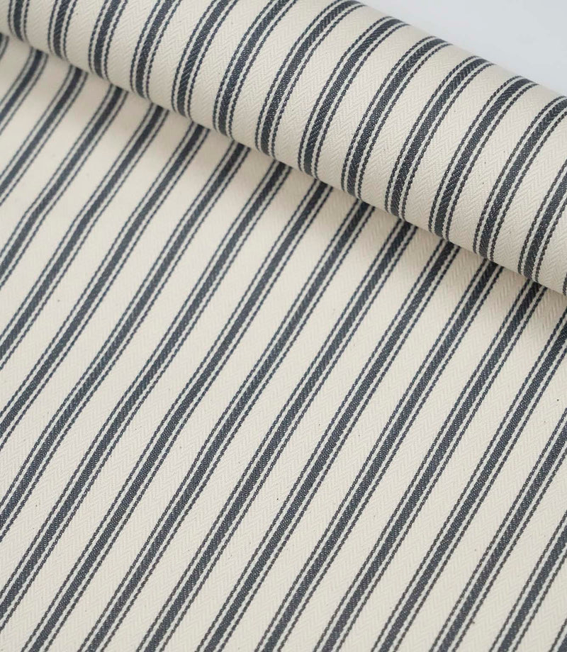 Rolled grey ticking stripe fabric highlighting the classic striped design and subtle woven herringbone texture.