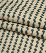 Folded indigo striped fabric revealing the soft drape, classic ticking pattern, and textured herringbone weave on an ivory background.