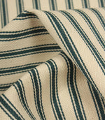 Detailed close-up of folded ticking stripe fabric featuring deep indigo stripes, textured weave, and a soft natural ivory ground.