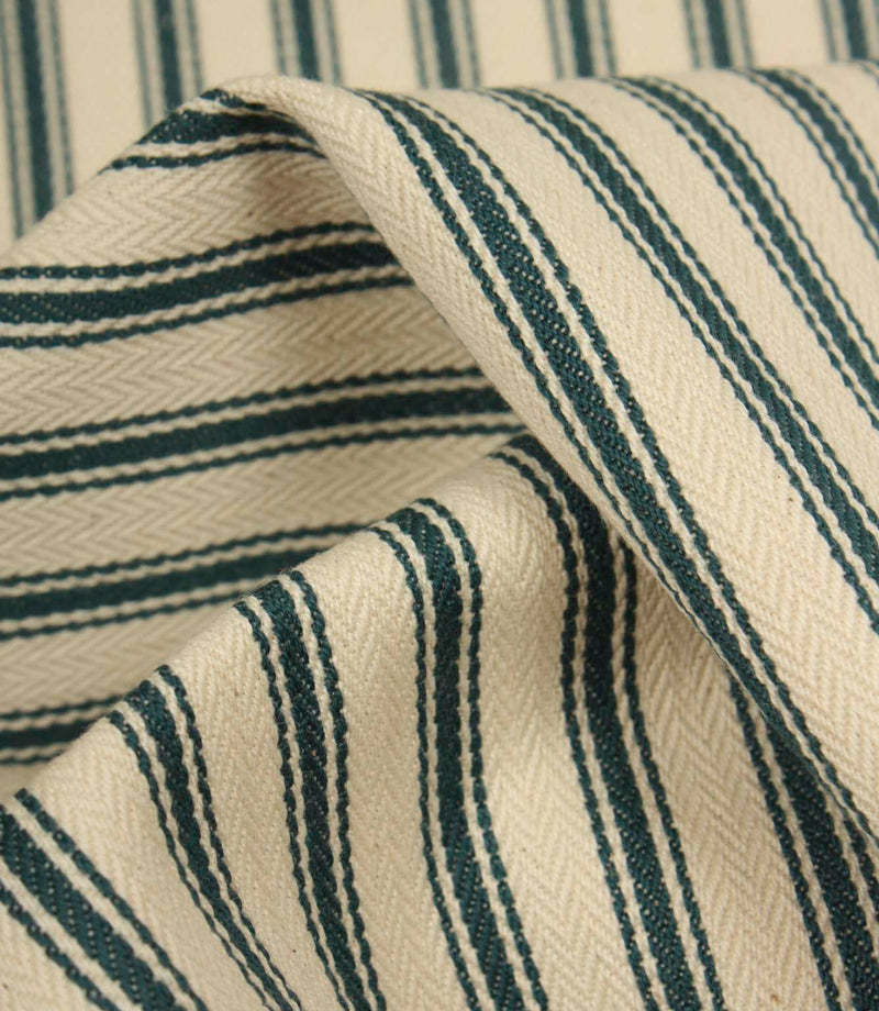 Detailed close-up of folded ticking stripe fabric featuring deep indigo stripes, textured weave, and a soft natural ivory ground.