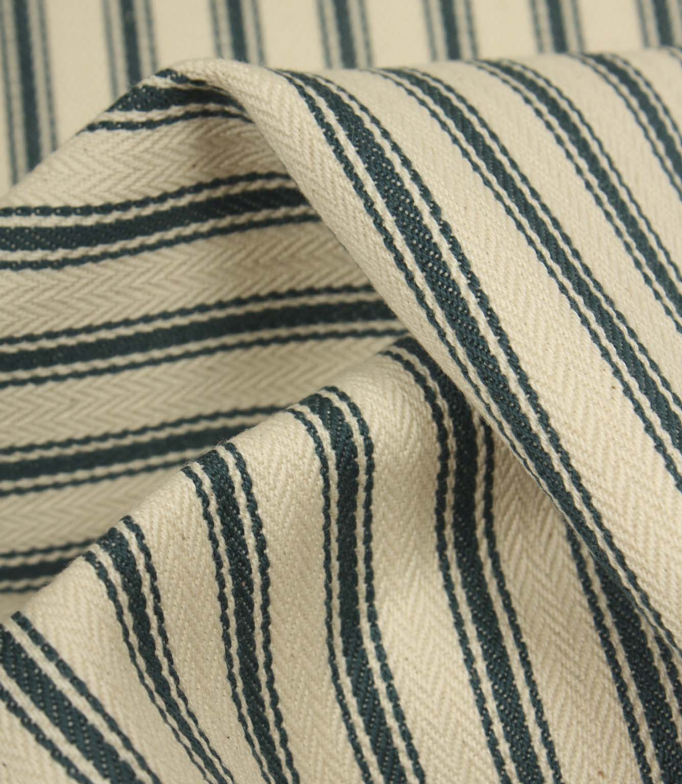 Detailed close-up of folded ticking stripe fabric featuring deep indigo stripes, textured weave, and a soft natural ivory ground.