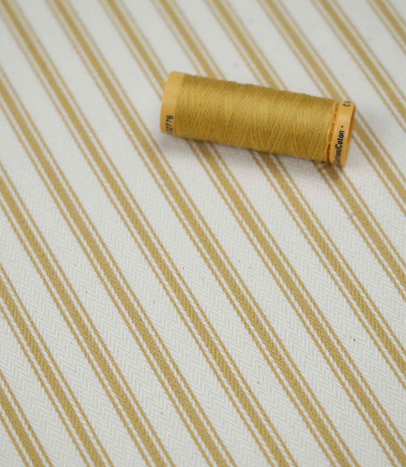 Ochre ticking stripe fabric with matching ochre thread, ideal for upholstery, curtains, blinds and sewing projects.