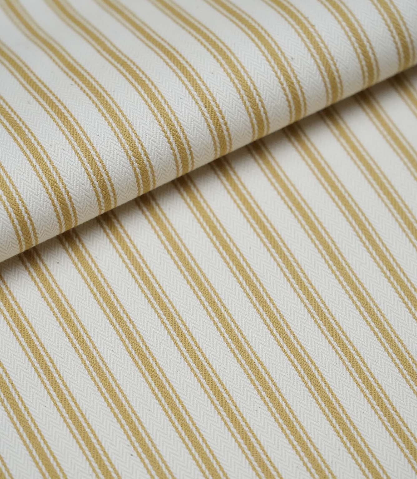 Folded ochre ticking stripe fabric showcasing the timeless striped pattern and premium woven herringbone finish.