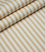 Layered folds of ochre ticking stripe fabric displaying the fine herringbone weave and classic striped design.
