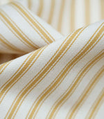 Close-up detail of ochre ticking stripe fabric showing the fine woven texture and warm ochre stripe pattern.