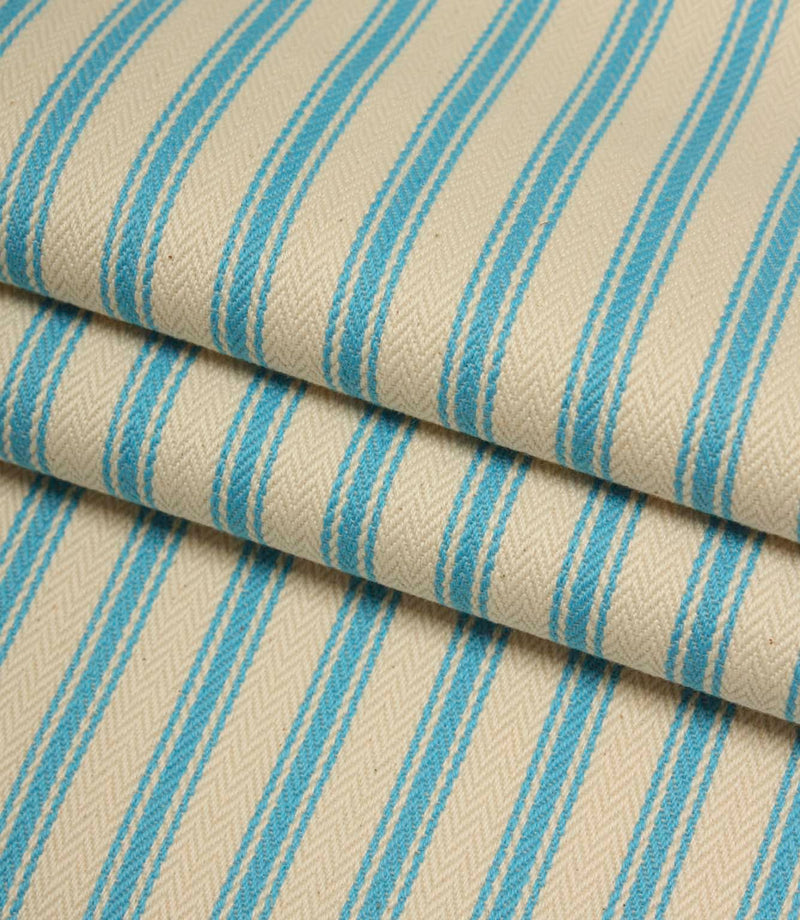Folded ivory and Pacific blue striped ticking fabric highlighting the woven herringbone texture and soft drape.