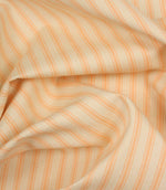 Draped peach ticking stripe fabric highlighting elegant folds and the timeless woven stripe pattern.