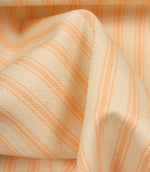 Detailed close-up of peach striped ticking fabric with visible herringbone weave and soft fabric drape.