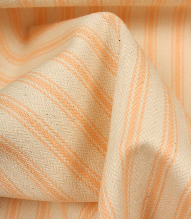 Detailed close-up of peach striped ticking fabric with visible herringbone weave and soft fabric drape.