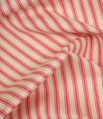 Draped petunia pink ticking stripe fabric highlighting flowing folds and the classic woven stripe pattern.