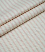 Layered folds of pink ticking stripe fabric displaying the fine herringbone weave and classic striped design.