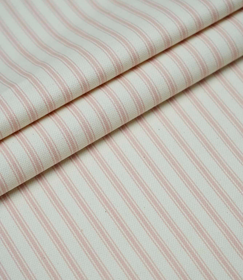 Layered folds of pink ticking stripe fabric displaying the fine herringbone weave and classic striped design.